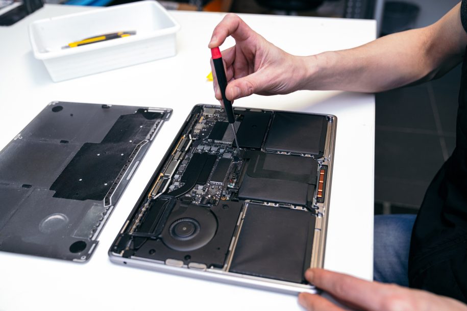 Hands of a skilled technician detaching components inside a laptop.