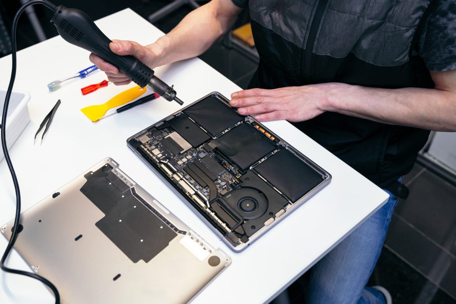 Heat gun in use on a laptop for repair at a technician's station.