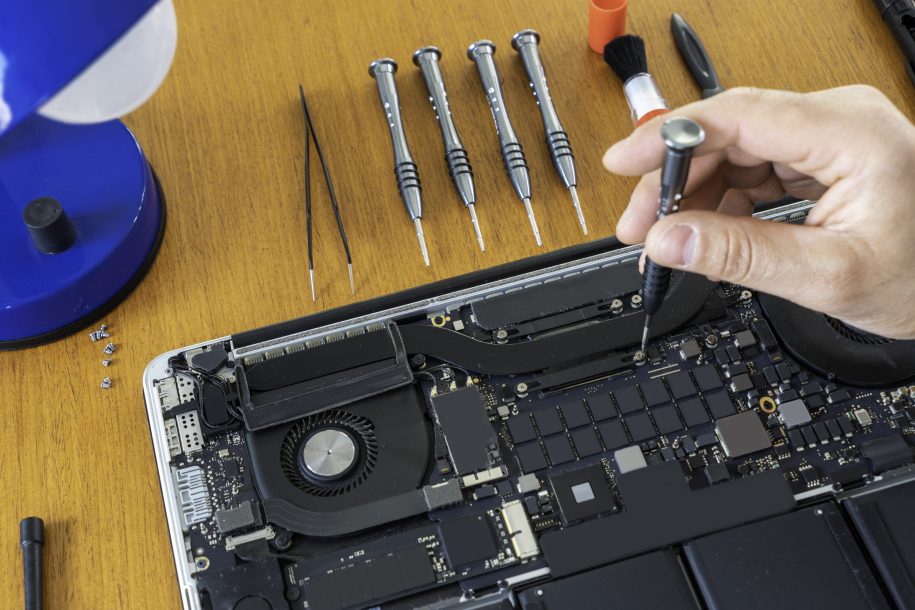 A technician's hands repairing disassembled laptop