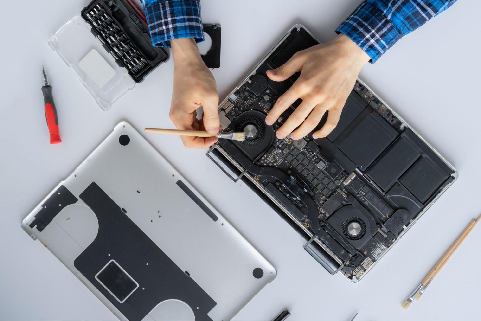 A technician from the best laptop repair shop carefully cleaning internal laptop components.