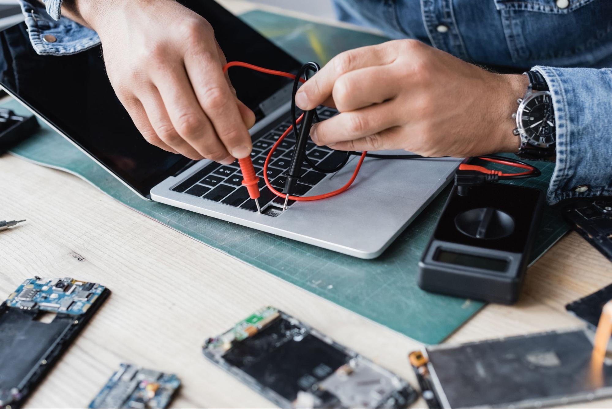 A person removing faulty components and installing a new MacBook keyboard replacement.