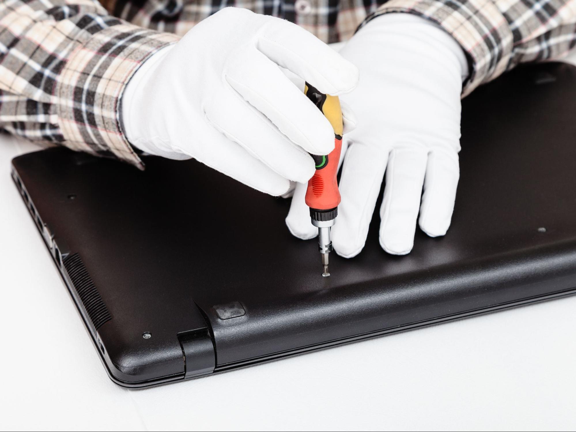 Close-up of hands securing a laptop with screws post-repair at the best laptop repair shop
